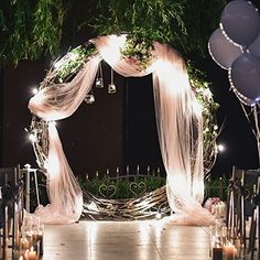 a wedding arch decorated with white drapes and candles is lit up for the ceremony