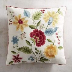 a white pillow with red, yellow and blue flowers on it's back side