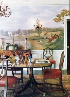 a dining room table with two chairs and a painting on the wall behind it,