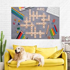 a dog sitting on a couch in front of a wall with scrabbles and crayons