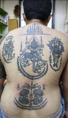 the back of a man with tattoos on his body and an anchor in the middle