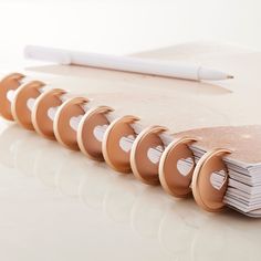 a stack of notebooks sitting on top of a table next to a white pen