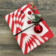 a red and white striped wrapping paper on top of a wooden table with a christmas ornament