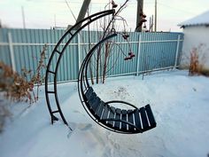 a circular metal bench sitting in the snow