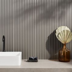 a bathroom with a sink, mirror and vase in front of the wall that has vertical slats on it