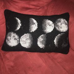 a black and white crochet pillow with nine phases of the moon on it