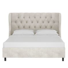 an upholstered bed with white linens and tufted headboard, viewed from the side