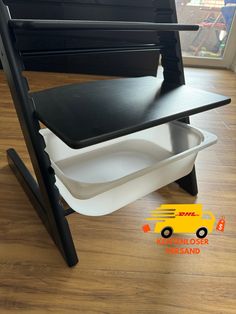 a black and white chair with a yellow truck on the bottom shelf next to it