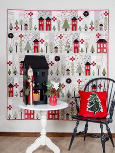 a table with a christmas scene on it next to a chair and wall hangings