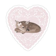 a small deer laying on top of a heart shaped doily