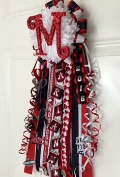 the letter m is made out of red, white and black ribbons with silver sequins