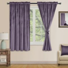 a living room filled with furniture and a window covered in purple drapes next to a chair