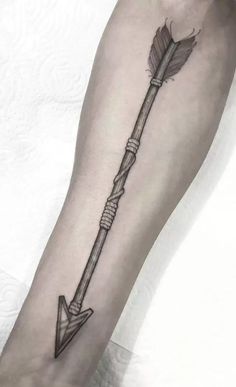 a black and white photo of a person's arm with an arrow tattoo on it