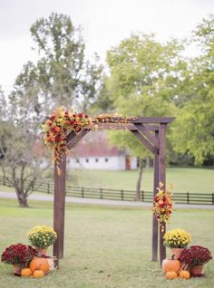 an outdoor wedding arch with flowers and pumpkins