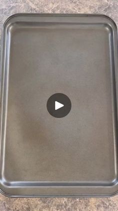 an empty metal tray with a play button on the side and a black circle in the middle