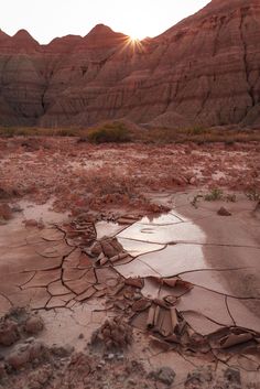 the sun shines brightly over an arid area with cracked rocks and water in it