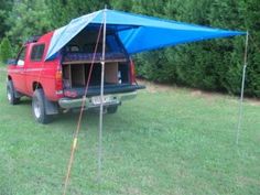 a red truck with a blue tarp on it's back parked in the grass