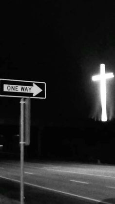 a one way street sign in front of a cross