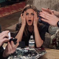 a woman covering her eyes as she sits at a table with other people around her