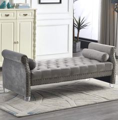 a gray bench sitting on top of a rug in front of a white dresser and mirror