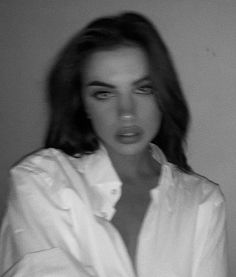 a black and white photo of a woman with long hair wearing a button up shirt