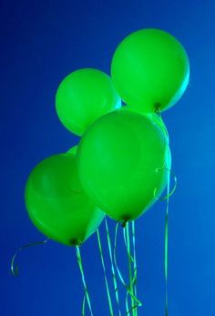 green balloons floating in the air against a blue sky