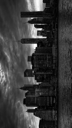 black and white photograph of the empire state building in new york city, with clouds overhead