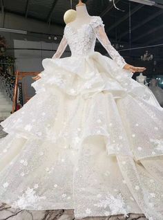 a white wedding dress with long sleeves and flowers on the skirt is displayed in front of a