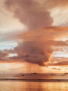 the sun is setting at the beach with boats in the water