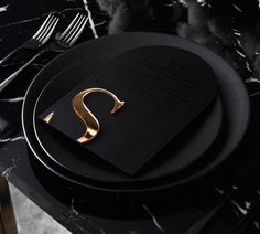 a black plate with a gold letter on it