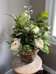 a basket filled with white flowers sitting on top of a wooden table next to a window