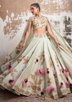 Editor's Note Featuring a mint green embroidered lehenga set, embellished with gold and pink thread work & highlighted with gold sequin hand embroidery. The lehenga and dupatta are accentuated with hand made 3D floral corsages with feathers in tones of pink and maroon. Fabric: Chanderi & organza Color: Green, gold Component: Lehenga , blouse and dupatta Occasion: Haldi mehndi and engagement Note: Product colour may slightly vary due to photographic lighting sources Care: Dry Clean Only About the Gold Corsage, Pastel Lehenga, Pink And Maroon, Maroon Fabric, Haldi Outfit, Floral Lehenga, Indian Wedding Outfit, Pink Thread, Green Lehenga