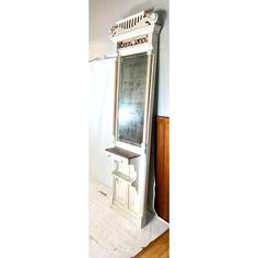 an old mirror sitting on top of a wooden floor next to a wall mounted shelf