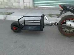 a motorcycle with a trailer attached to it's back wheel on the street next to a building