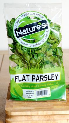 a bag of flat parsley sitting on top of a cutting board