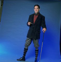 a man with a cane is standing in front of a blue background and posing for the camera