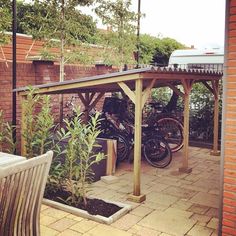 there are many bikes that are parked under the pergolated area on this patio