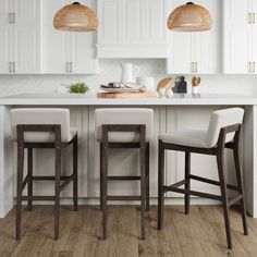 three stools in front of a kitchen island with white cabinets and countertop space