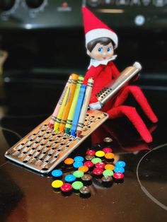 an elf is sitting on the counter with some candy and crayons