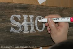 someone is writing the word sho on a wooden sign