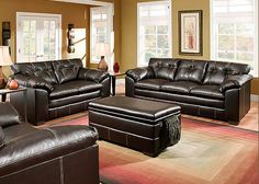 a living room filled with brown furniture and lots of windows