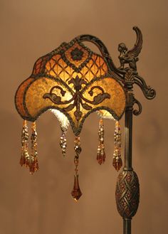 a lamp that is sitting on top of a wooden stand with beads hanging from it's sides