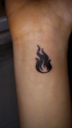 a small tattoo on the arm of a person with a black fire symbol in it