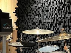 a drum set up in front of a wall with black and white tiles on it