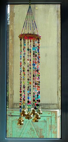 a bunch of bells hanging from a window sill in front of a green cabinet