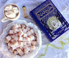 a bowl of marshmallows next to a book and cup of coffee