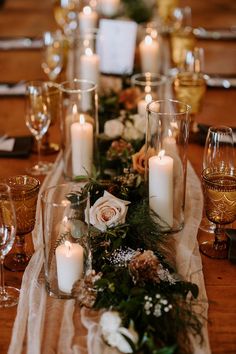 the table is set with candles, flowers and greenery for a festive look