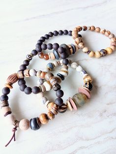 Earthy, natural, cozy, and everyday. Beautiful beige, white, cream, brown, and touches of sienna and rust in these mixed medium stack bracelets. Several gemstone varieties in different sizes, finishes, and colors. Several Jaspers, Tibetan Agate, Fossilized Coral, Picture Jasper rondelle, and many ethical bone beads in a variety of colors and shapes. Mix these in with recycled glass, Ebonywood, beads, Kente Krobe sand glass beads, shell, coconut disks, and mixed metals. Unique and stunning. Strun Hand Wrapped Brown Beaded Bracelets For Meditation, Rustic Brown Bracelets With Natural Stones, Handmade Nature-inspired Brown Bracelet, Nature-inspired Handmade Brown Bracelet, Artisan Brown Hand Wrapped Bracelets, Artisan Hand Wrapped Brown Bracelets, Handmade Brown Nature-inspired Bracelet, Nature-inspired Brown Beaded Bracelets With Natural Stones, Earthy Hand-strung Beaded Bracelets For Everyday