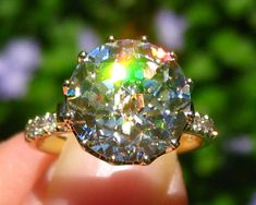 a close up of a person's hand holding a ring with a diamond in it