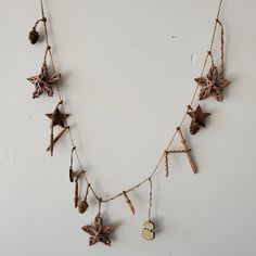 a wooden star garland hanging from a wall with pine cones and other items attached to it